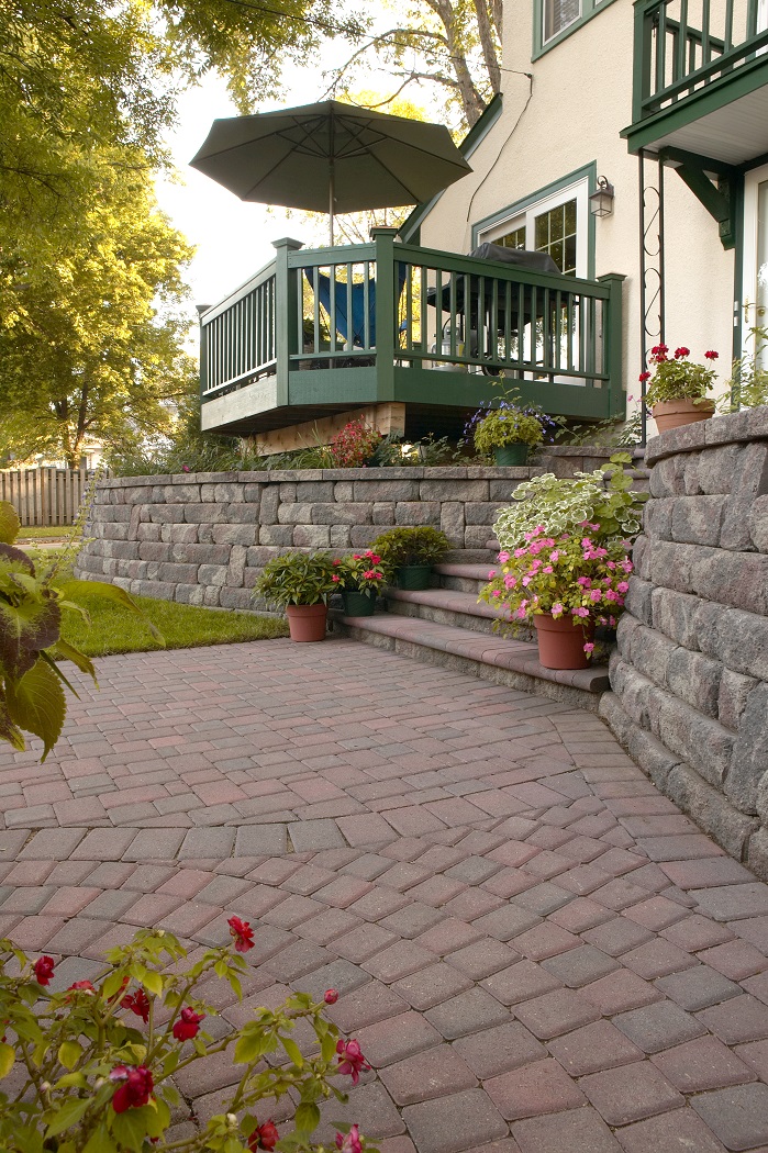 Green porch overlooking a paver patio with stone stairs and raised Bayfield retaining wall planters
