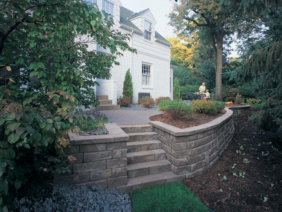 White home with stone stairway and raised Bayfield retaining wall concrete block planters