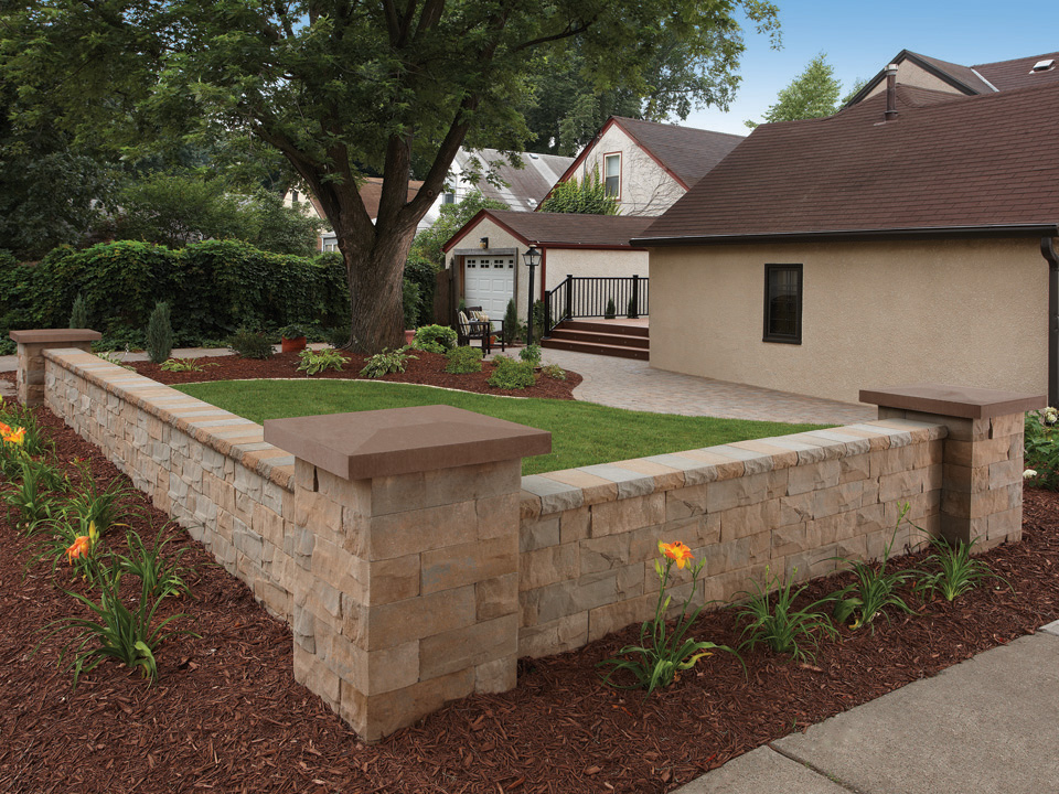 Corner of grassy lawn and planting area separated by Brisa freestanding concrete block walls
