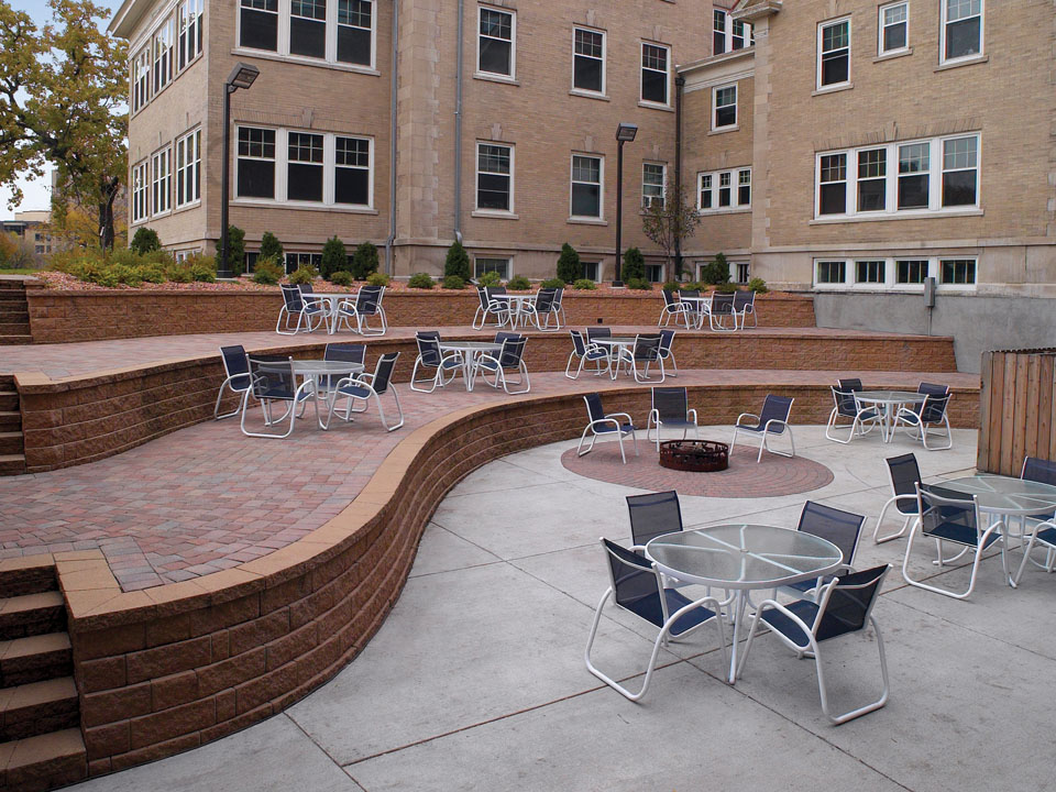 Terraced Diamond Pro straight face retaining wall patio courtyard with tables, chairs and a fire pit