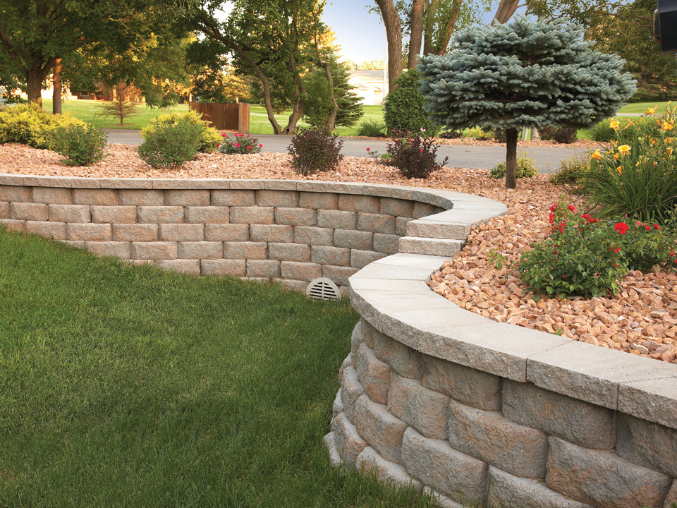 Close view of terraced Diamond Pro stone cut casual face retaining wall planting area with pink lilies