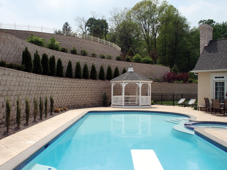 Close view of poolside terraced curved Diamond Pro beveled concrete stone retaining wall planting areas