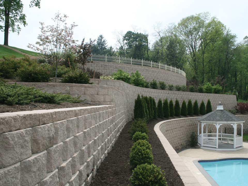 Close view from above of poolside terraced curved Diamond Pro beveled concrete stone retaining wall planting areas