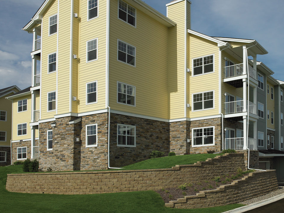 Rear of apartment building with raised lawn surrounded by a curved Diamond Pro Diamond Pro stone cut retaining wall