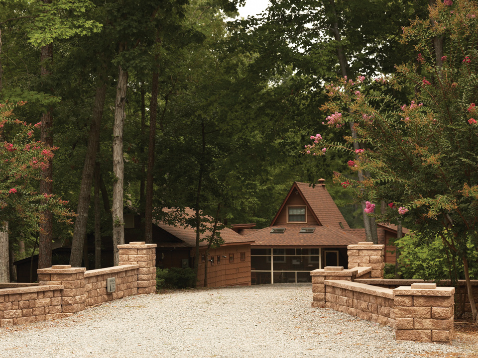 Highland Stone freestanding concrete block walls leading to a brown house in the woods 