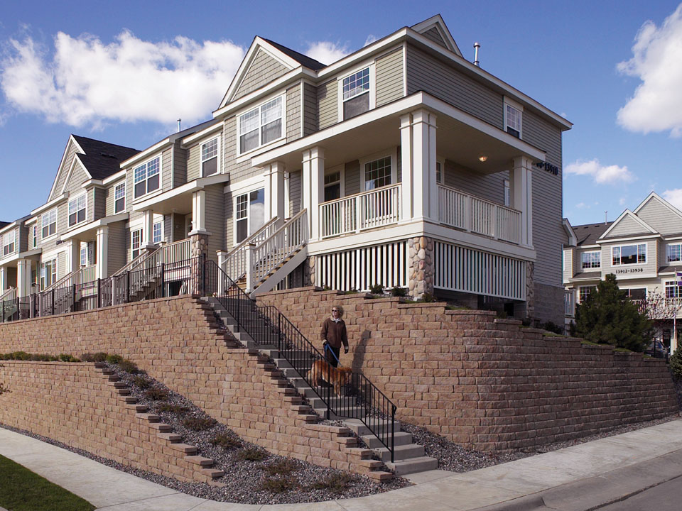 Townhomes with sloped lawns surrounded by curved Highland Stone concrete block retaining walls and built-in stairway
