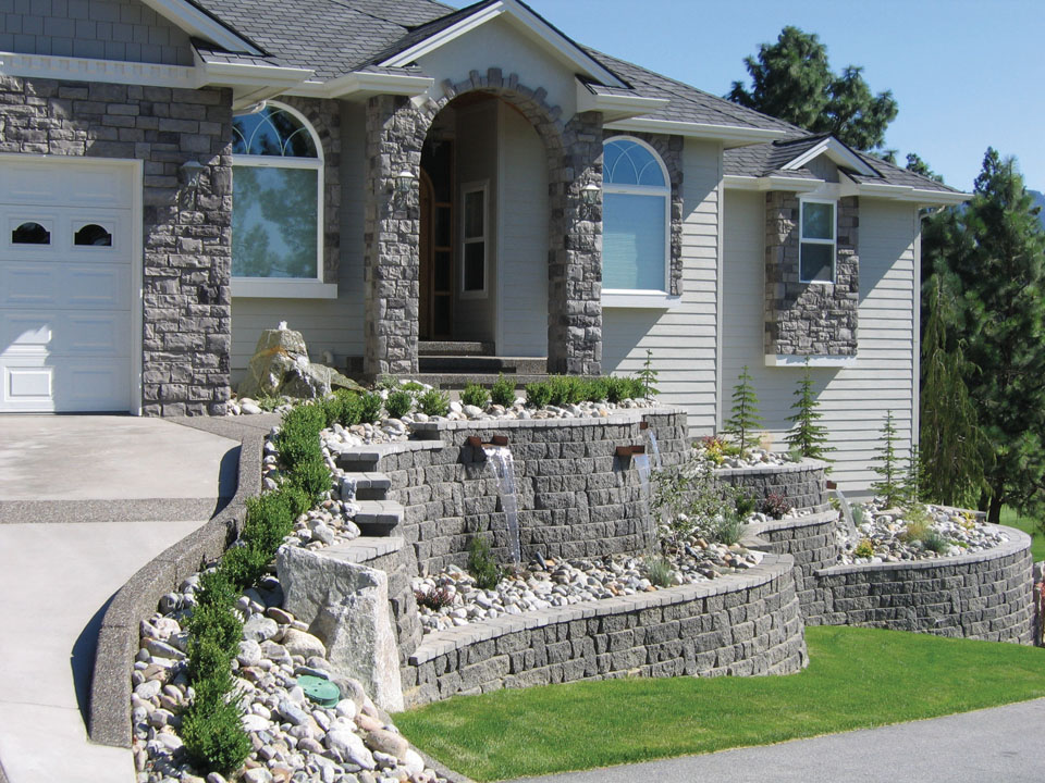 Grey home with curved terraced waterfall feature made from Highland Stone concrete block retaining walls