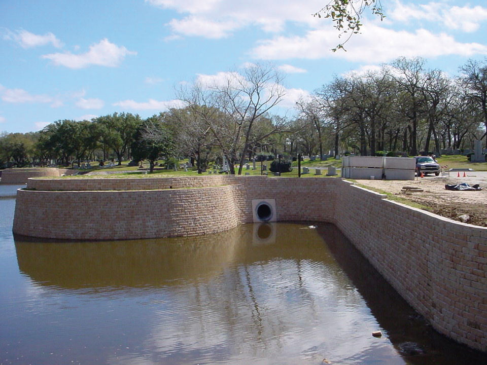 Cemetery and water feature separated by a curved terraced Highland Stone concrete block retaining wall