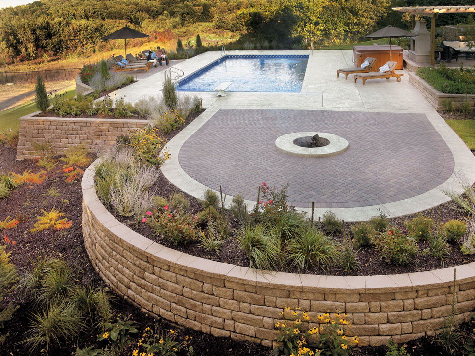 Swimming pool and curved paver fire pit area surrounded by raised Highland Stone concrete block retaining wall planters