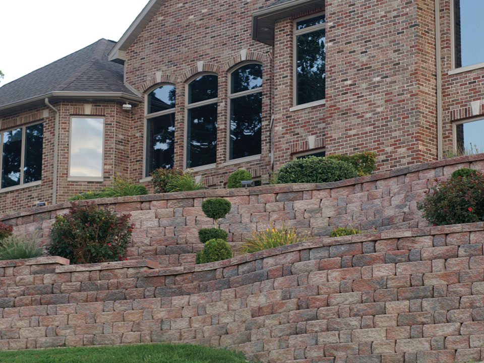 Brick home with raised terraced planters made from curved Highland Stone concrete block retaining walls