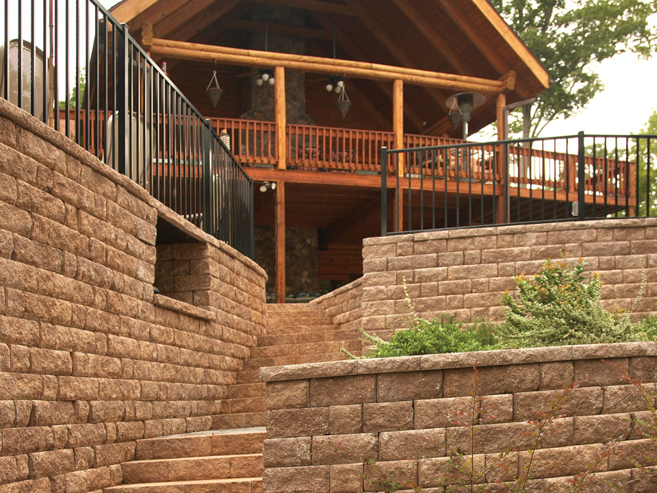 Stone stairway built into curved Highland Stone concrete block retaining walls topped with black wrought iron fences