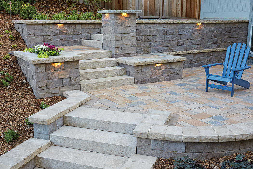 Raised concrete paver patio with inset Landings Step Units and raised concrete retaining wall planters with hidden light features. 