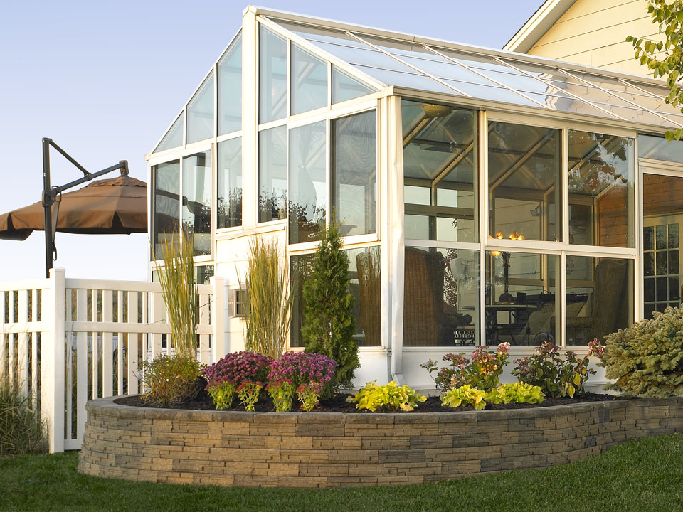 Residential greenhouse and raised circular LedgeWall concrete block retaining wall planter.