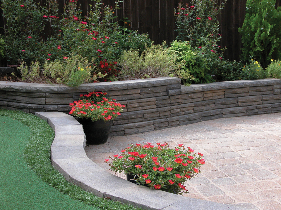 Paver patio with curved raised Natural Impressions Flagstone concrete block retaining wall planter. 