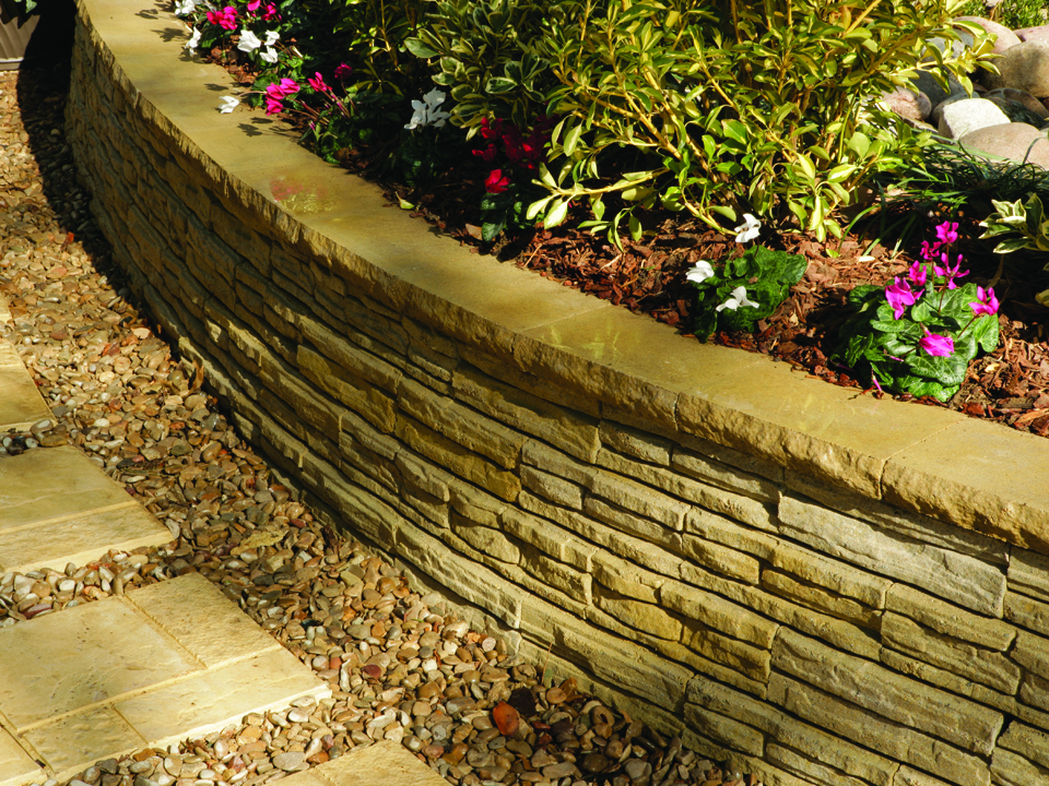 Close view of raised circular Natural Impressions Flagstone concrete block retaining wall planter and paving stone walkway. 